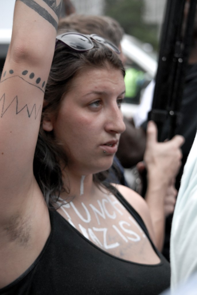 A girl raises her arm with "I punch Nazis" written on her chest in silver glitter during protest activity in Washington D.C. on Aug. 12, 2018. 